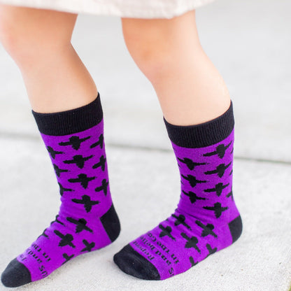 girl standing wearing Purple socks with black ash crosses that say "repent and believe in the gospel' across the toe